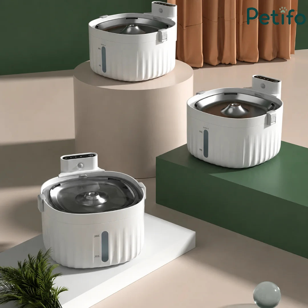 Three modern white automatic pet water fountains displayed together on tiered display pedestals.