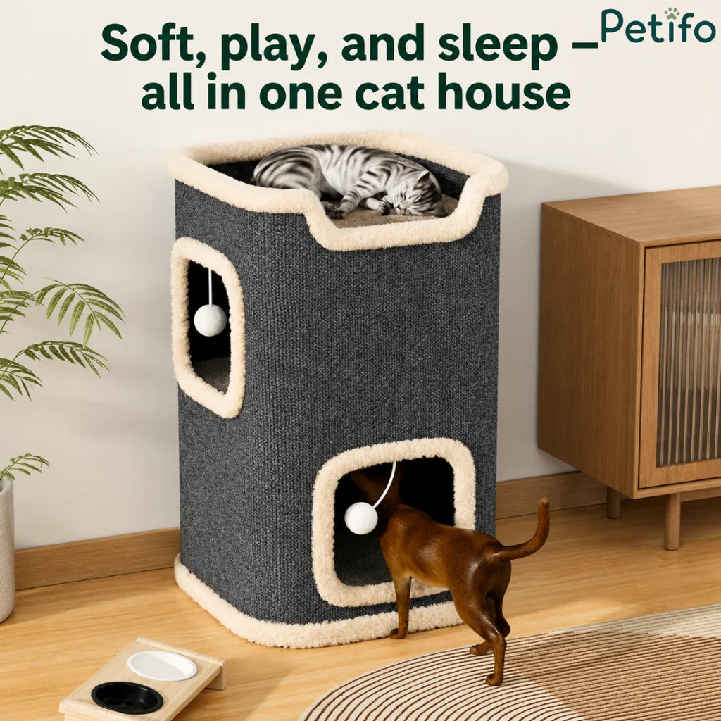 A Petifo cat house in a living room, with a cat sleeping on the top level and another playing inside the base level.