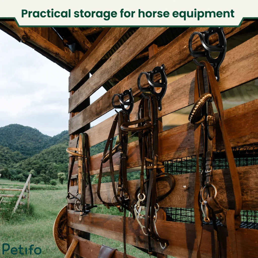 Black metal bridle racks mounted on a rustic wooden stable wall overlooking a scenic landscape.