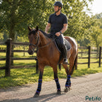 Equestrian rider on a brown horse wearing blue cooling therapy boots outdoors.