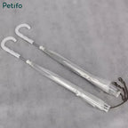 Two folded clear pet umbrellas packaged together with their C-shaped handles and hanging chains visible.
