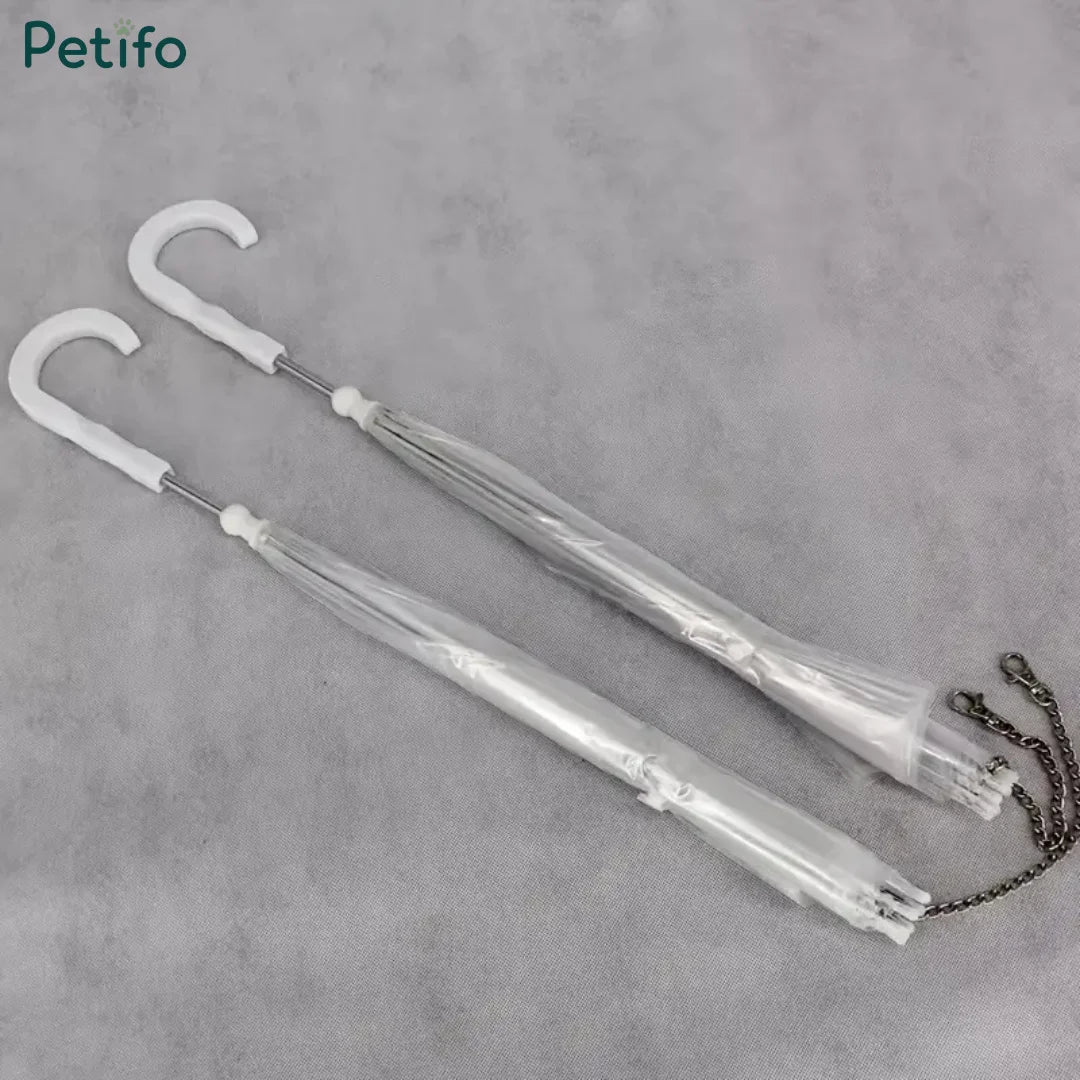 Two folded clear pet umbrellas packaged together with their C-shaped handles and hanging chains visible.