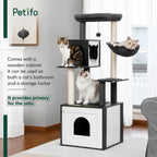 A Petifo cat tree in a living room setting, highlighting the base wooden cabinet that serves as both a storage locker and a private bathroom for cats.