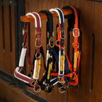 Assorted colorful padded horse halters hanging on a wooden tack rack.