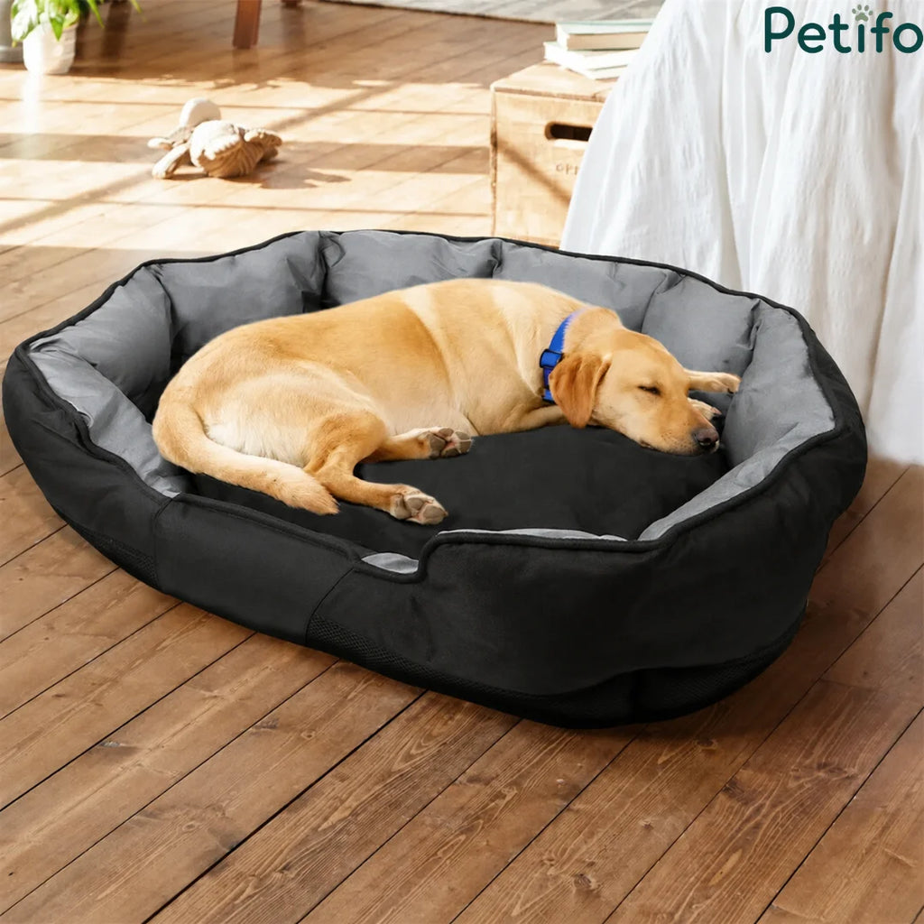Comfortable large dog sleeping in a cozy black pet bed on a wooden floor.