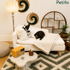 A Boston Terrier in a bathrobe relaxing on a luxury white plush pet sofa in a decorated living room.