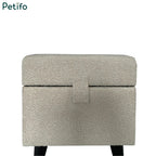  A closed cream-colored textured fabric pet pouffe with a central tab fastener.