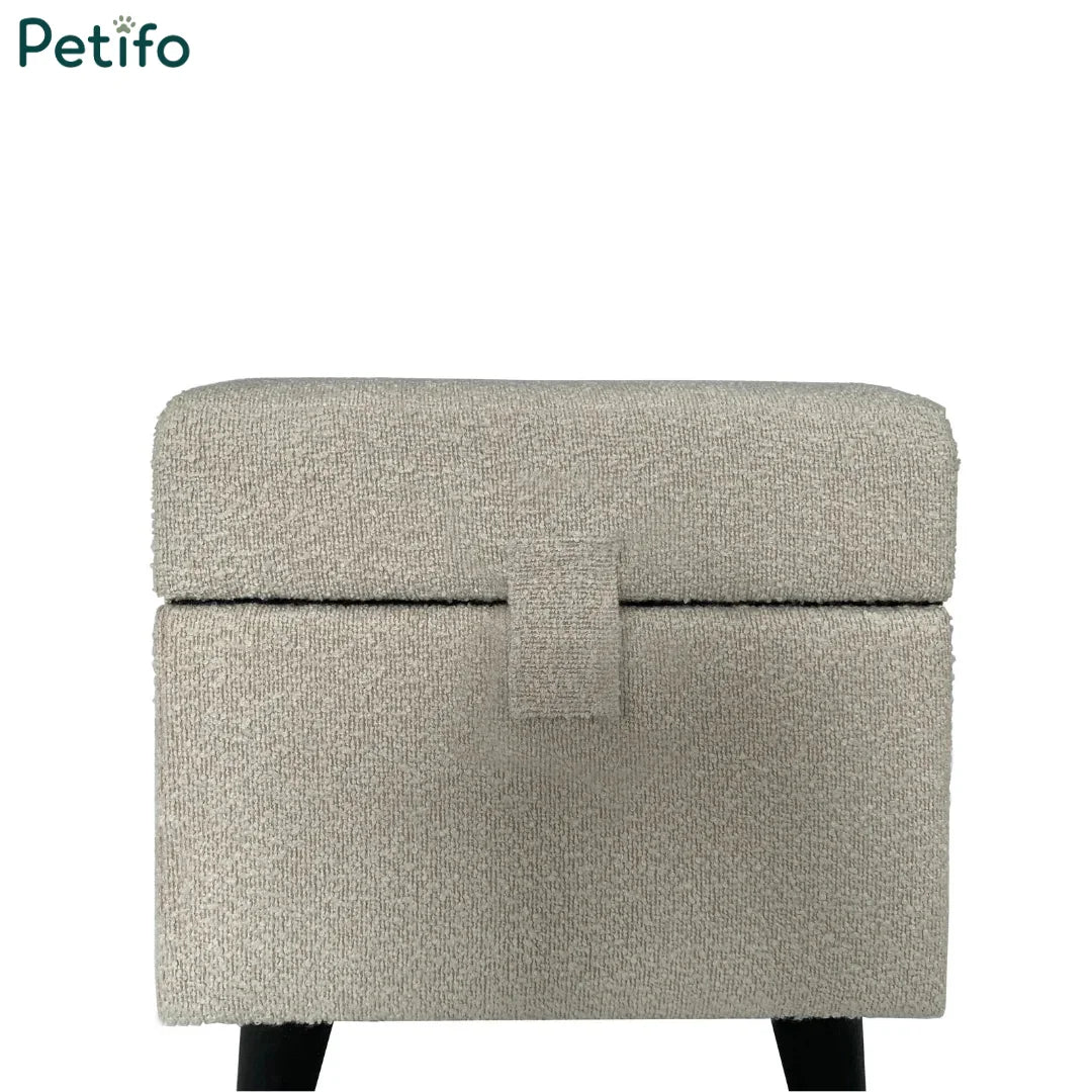  A closed cream-colored textured fabric pet pouffe with a central tab fastener.