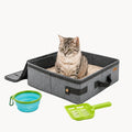 Grey portable cat litter box with a cat inside, accompanied by a blue collapsible bowl and green scoop on a white surface.