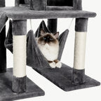 A cat resting comfortably inside a hanging plush hammock on a dark grey multi-level cat tree.