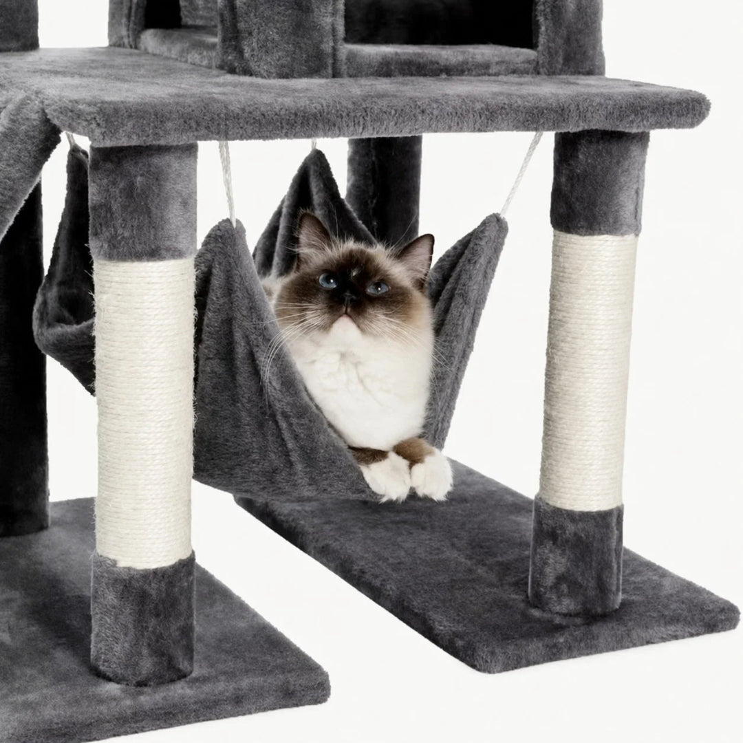A cat resting comfortably inside a hanging plush hammock on a dark grey multi-level cat tree.