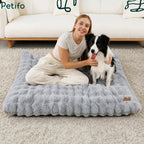 Happy woman sitting on a comfortable, grey plush Petifo dog bed with her Border Collie at home.