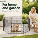 Puppy inside the wire playpen set up on a home patio next to a sitting woman.