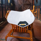 White quilted saddle pad displayed on a wooden saddle rack inside a stable.