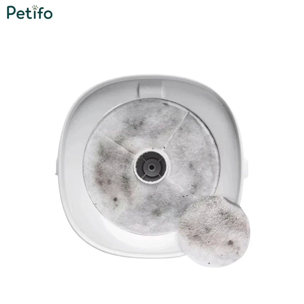 Top-down view of a white automatic pet water fountain holding a multi-stage replacement filter with a separate filter disc in the foreground.