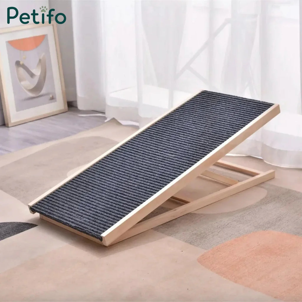 An adjustable wooden ramp for pets featuring a non-slip, ribbed surface positioned on a rug in a bright room.