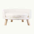white elevated pet bed with wooden legs in a cozy home interior.