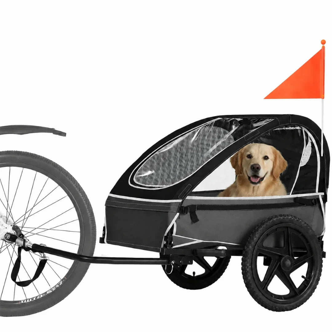 A black and grey pet bike trailer with a high-visibility safety flag, featuring a golden retriever looking out from the cabin.