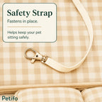 Close-up of a cream-colored safety strap with a gold metal clasp resting against a beige and white gingham pattern background, labeled with the text "Safety Strap: Fastens in place. Helps keep your pet sitting safely." and the Petifo logo.
