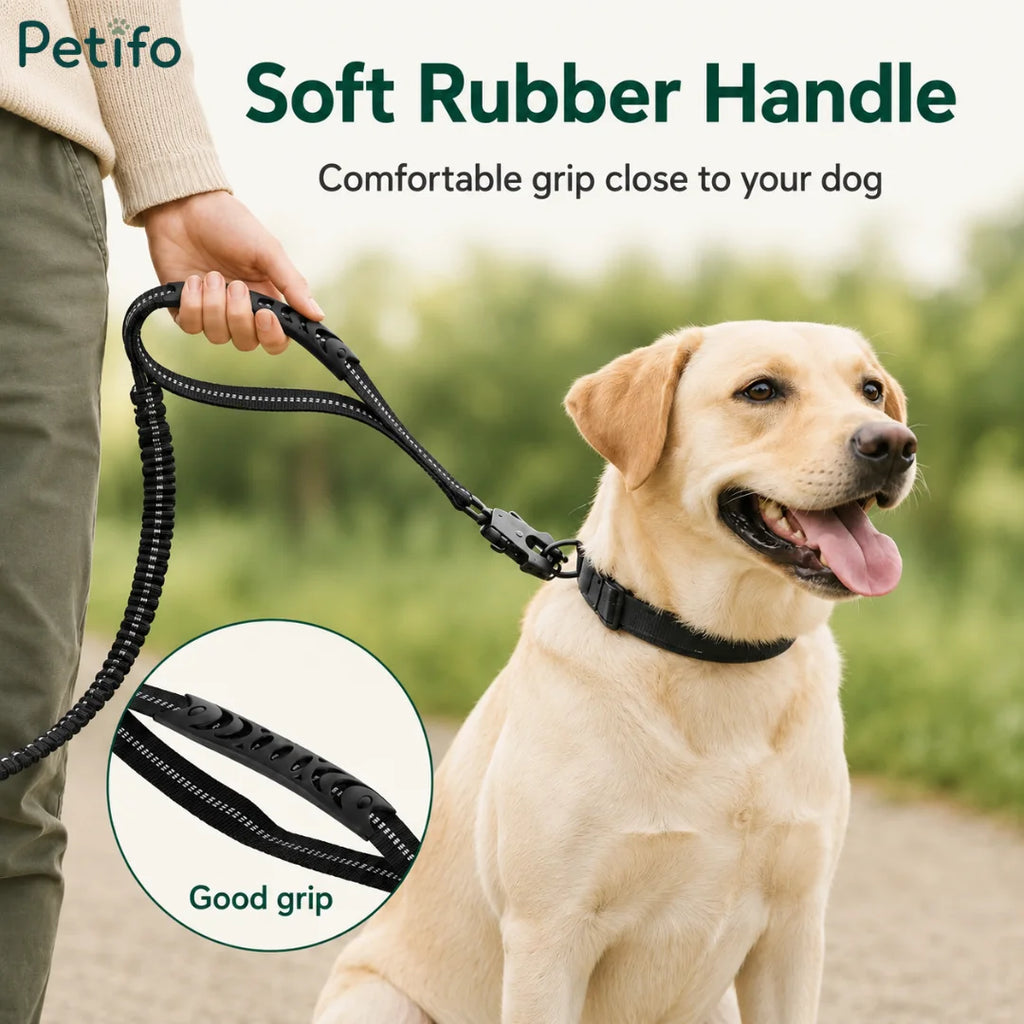 Person holding the soft rubber handle of a black bungee dog leash while walking a happy labrador outdoors.