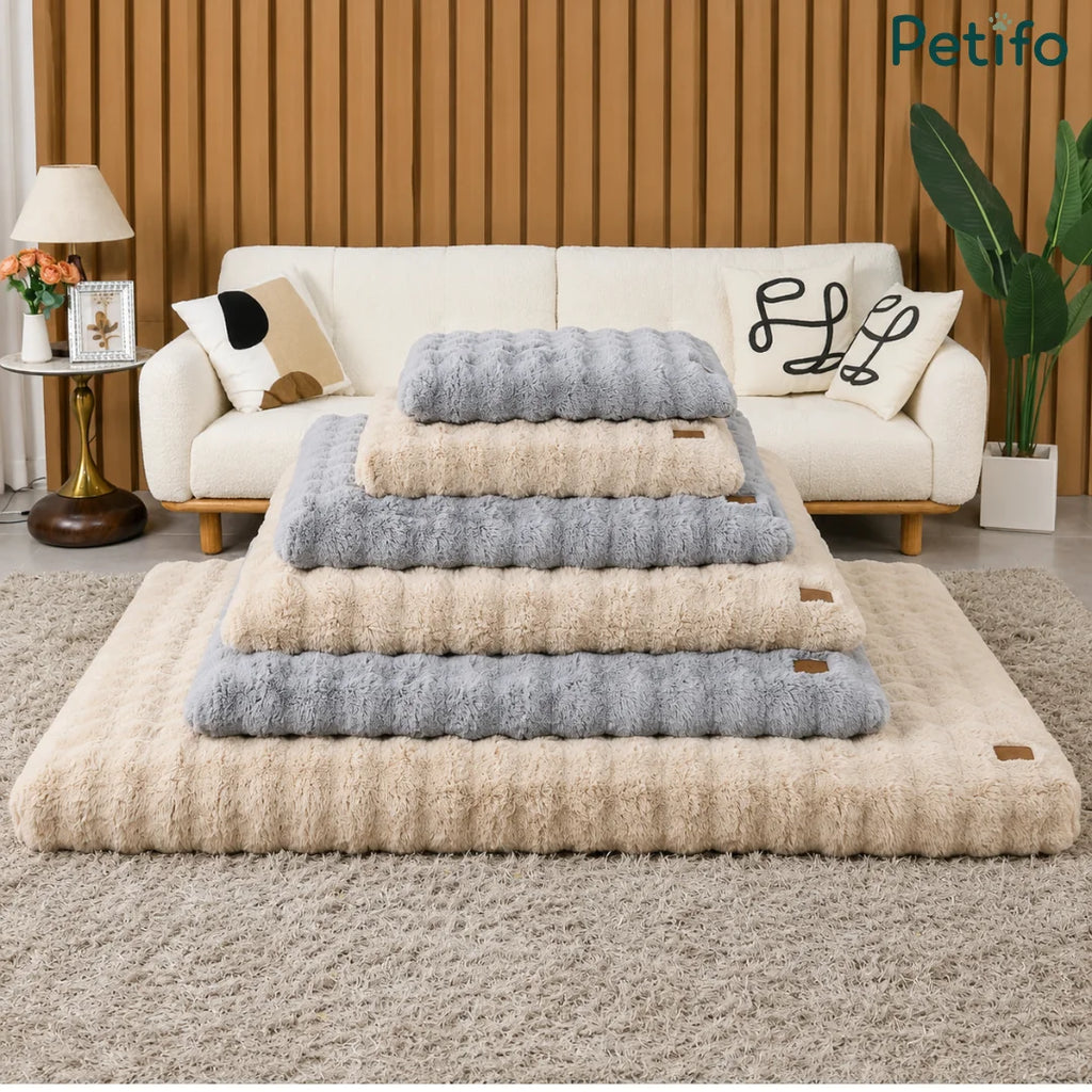 Stack of various sizes and colors of Petifo plush pet beds displayed in a stylish living area.