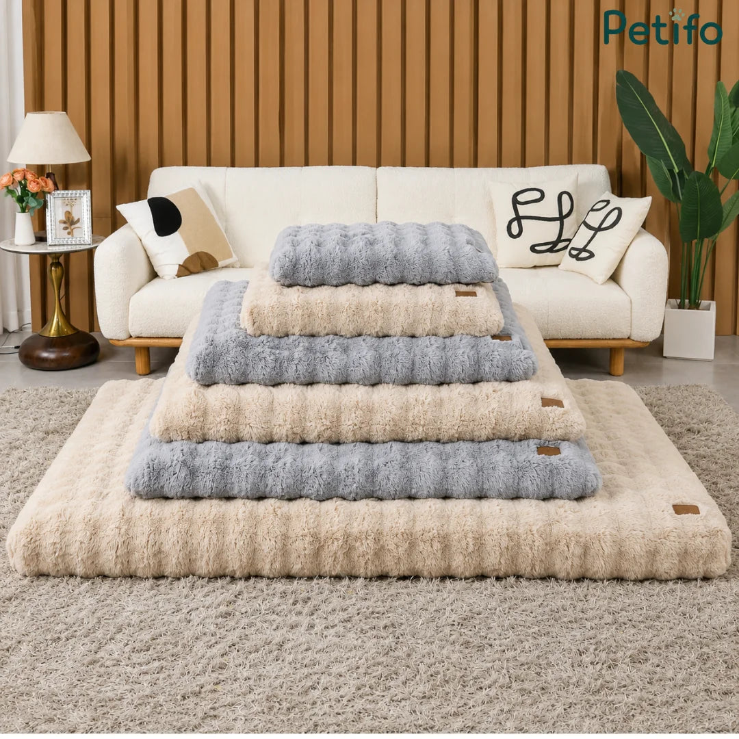 Stack of various sizes and colors of Petifo plush pet beds displayed in a stylish living area.