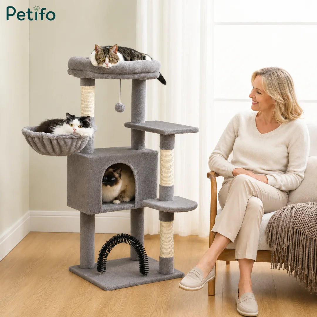 Three happy cats relaxing on different levels of a sturdy, plush grey cat tree in a cozy living room setting.