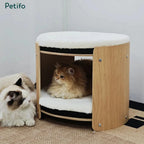 A stylish round two-story cat house with natural wood finish and soft bedding for multiple cats.