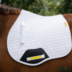 White quilted saddle pad placed on the back of a brown horse.