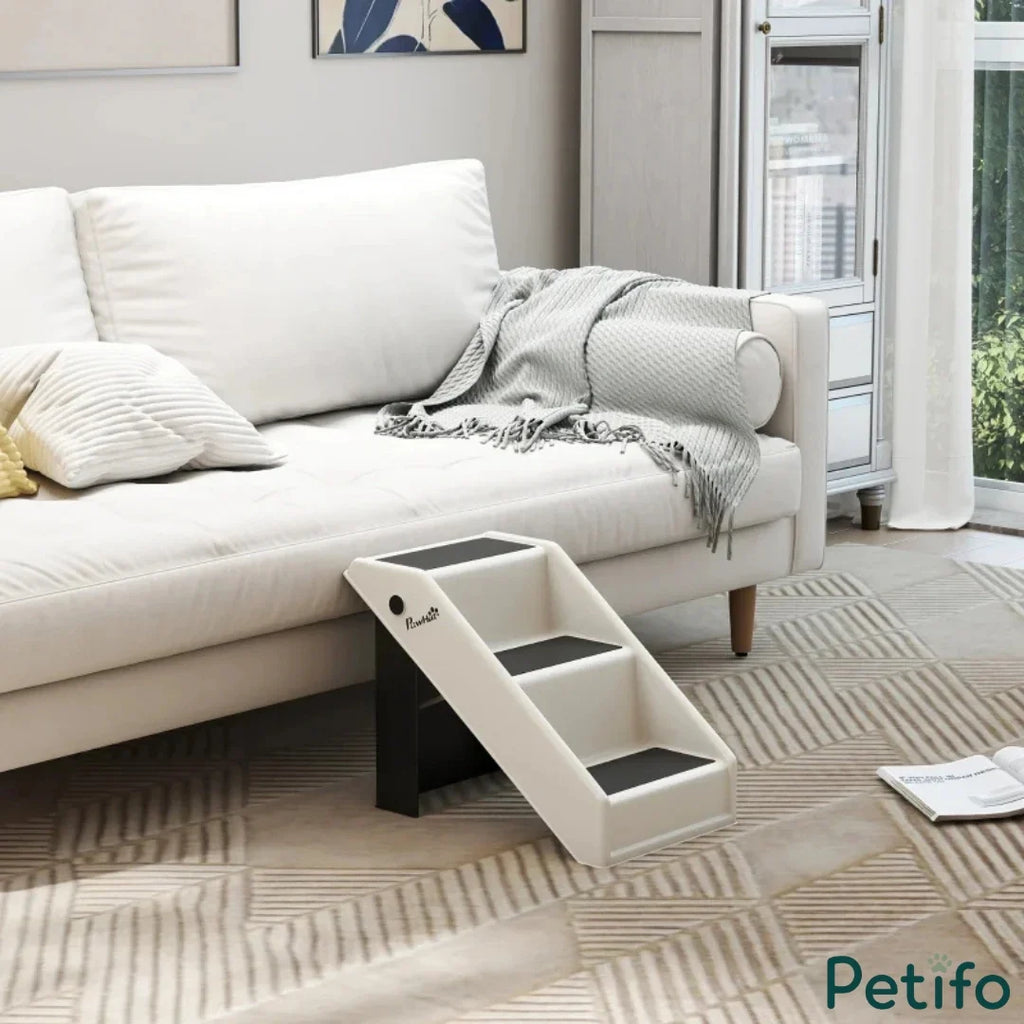 Empty white pet stairs placed next to a modern sofa.
